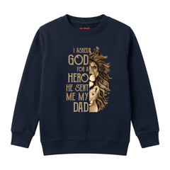 A navy blue crewneck sweatshirt featuring a graphic print of a lion half-severed from its human body, with the text 'I ASKED GOD FOR A HERO HE SENT ME MY DAD' in a gold serif font.